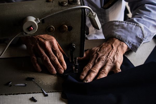 An upholsterer's hands guiding fabric through an industrial sewing machine
